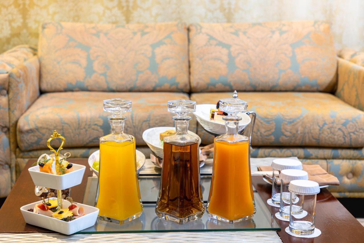 Al Aqeeq Madinah Hotel Medyna Zewnętrze zdjęcie The photo features a beautifully arranged table with several glass decanters filled with liquids. Two decanters, one containing a yellow drink (possibly juice) and another with a darker beverage (possibly tea), are placed prominently. In front of the